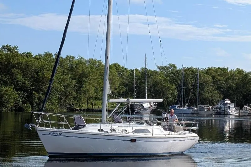 Slide: The Image of 2002 Catalina 34 Mark II sailboat on calm water with trees in the background. - 0