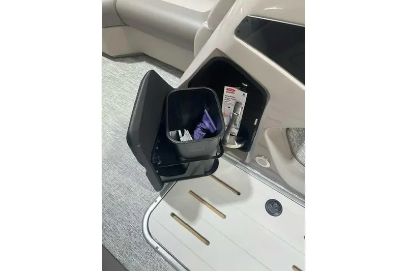 Slide: The Image of 2024 Premier 210 Sunsation RF boat storage compartment with cleaning supplies and trash bin. - 4