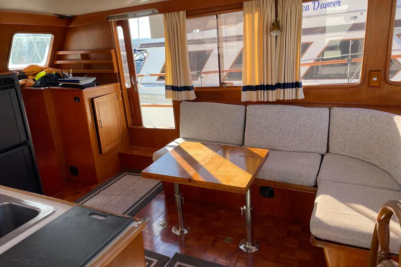 Slide: The Image of 1985 Ocean Alexander 38 Double Cabin interior with cozy seating and wooden table. - 10