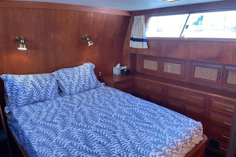 Slide: The Image of 1985 Ocean Alexander 38 Double Cabin bedroom with wood paneling and blue-patterned bedding. - 15