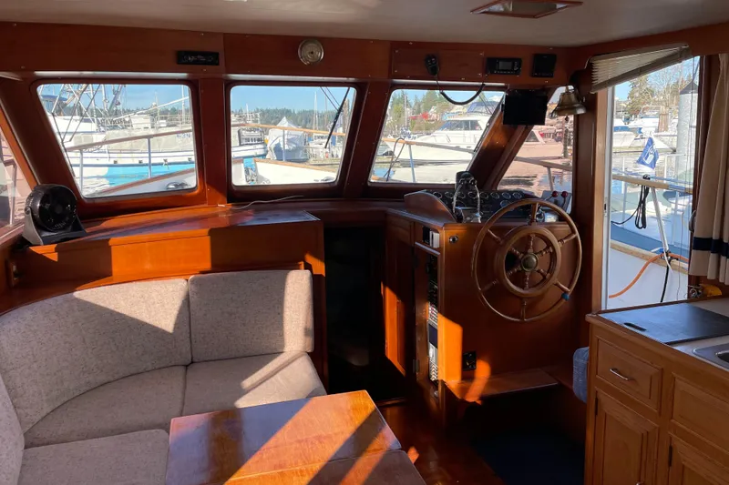 Slide: The Image of 1985 Ocean Alexander 38 Double Cabin interior with helm, seating, and marina view. - 9