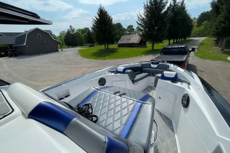 Slide: The Image of 2019 Sunsation 32 CCX boat interior with blue and gray seating, parked outdoors. - 3