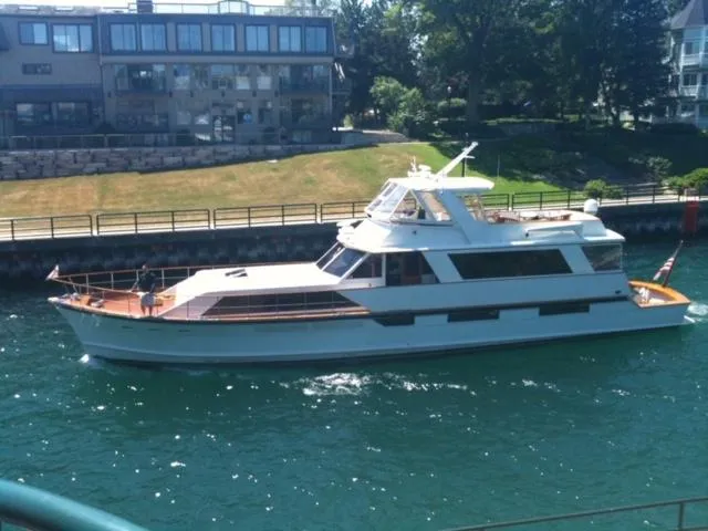 The Image of 1974 Pacemaker Cockpit Motoryacht cruising on a sunny day near waterfront buildings. - 0
