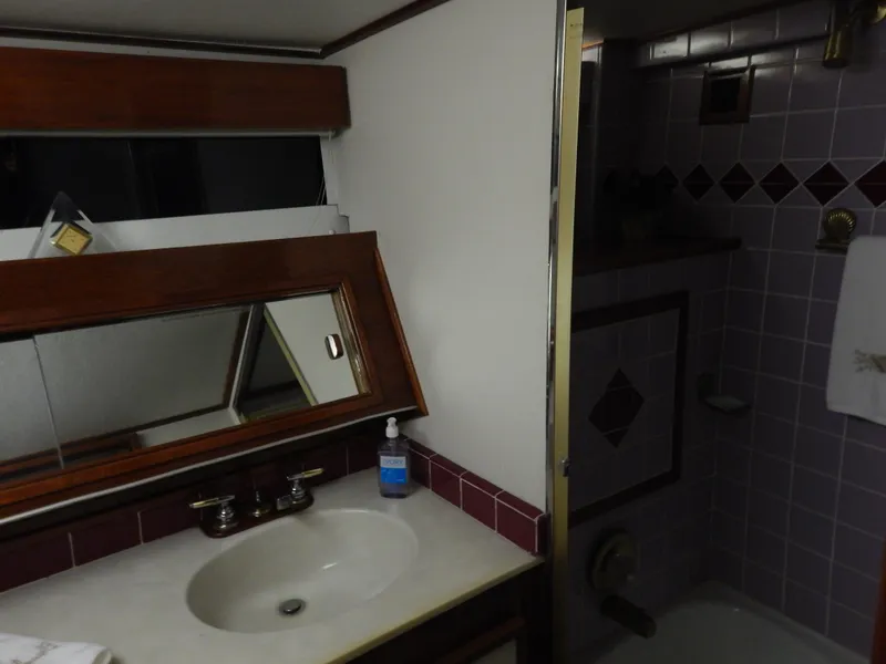 Slide: The Image of 1974 Pacemaker Cockpit Motoryacht bathroom with sink, mirror, and tiled shower area. - 20