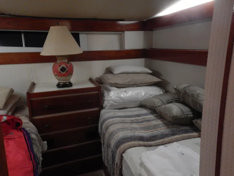 Slide: The Image of 1974 Pacemaker Cockpit Motoryacht cabin with twin beds, wooden dresser, and decorative lamp. - 23