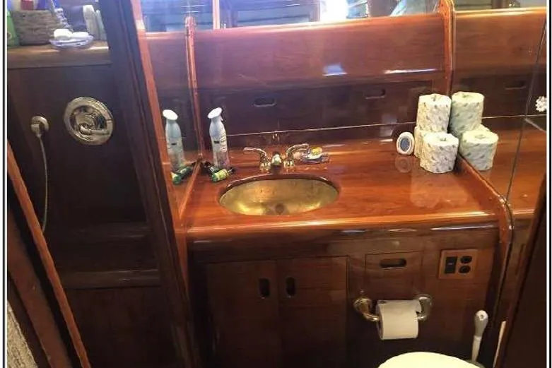 Slide: The Image of Luxurious wooden bathroom interior on 1974 Pacemaker Cockpit Motoryacht with brass sink and toiletries. - 42