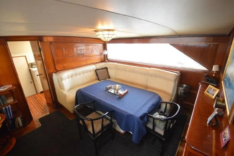 Slide: The Image of 1974 Pacemaker Cockpit Motoryacht interior with dining area, blue tablecloth, and wooden accents. - 60