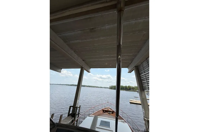 Slide: The Image of 1974 Pacemaker Cockpit Motoryacht docked under a covered structure, overlooking a serene lake. - 74