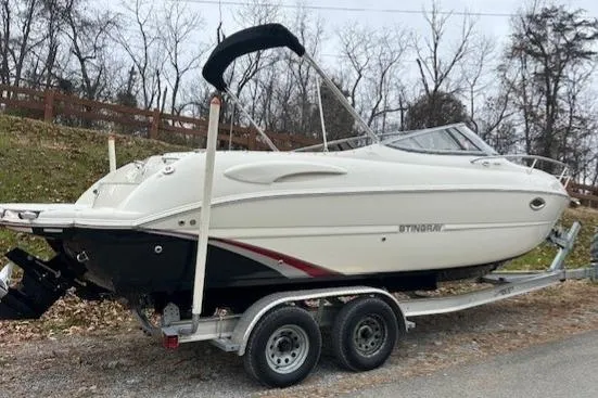 The Image of 2017 Stingray 250 CR boat on trailer, parked outdoors in a wooded area. - 0