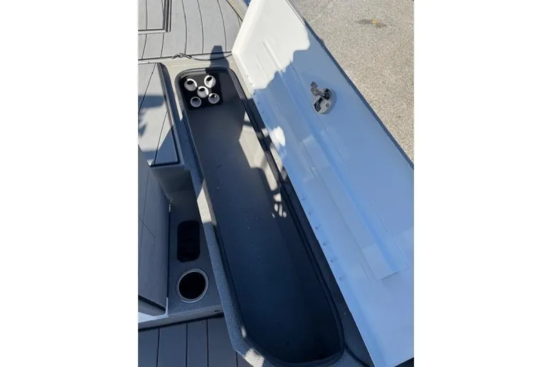 Slide: The Image of 2023 Vexus AVX1980CC boat storage compartment with cup holders, open lid, and sleek design. - 12