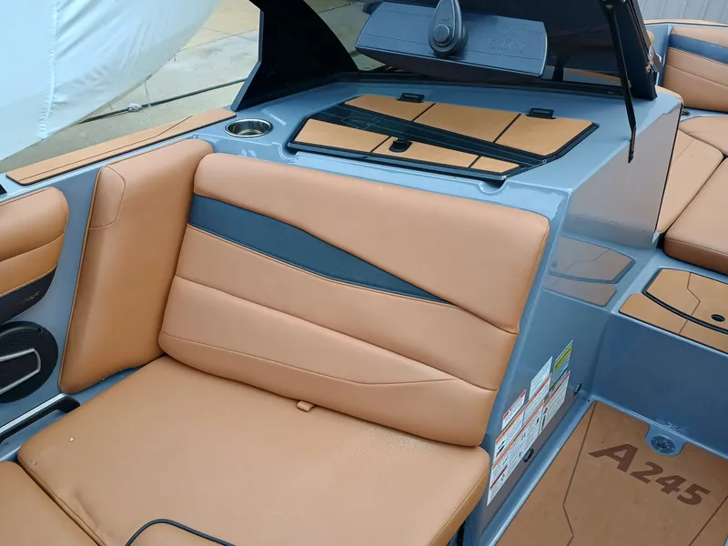 Slide: The Image of 2024 Axis A245 boat interior with tan and black seating, cup holder, and speaker. - 2