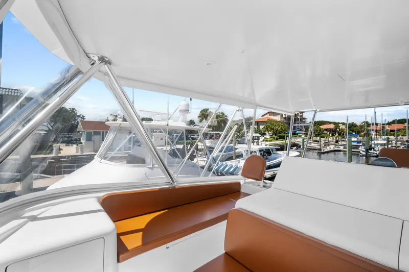 Slide: The Image of 2005 Viking 61 Convertible yacht interior with brown seating, docked at marina. - 11