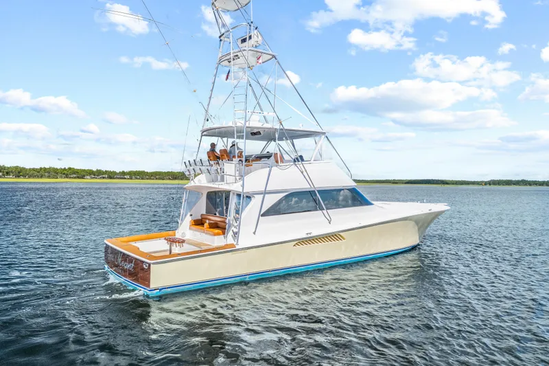 Slide: The Image of 2005 Viking 61 Convertible yacht cruising on a calm, scenic waterway under a clear blue sky. - 8