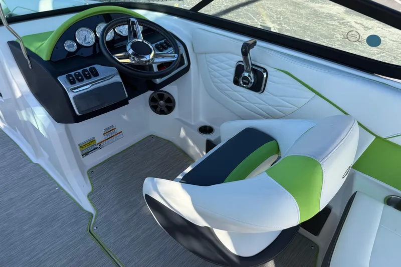 Slide: The Image of 2018 Regal 22 FasDeck boat cockpit with green and white seating, steering wheel, and controls. - 10