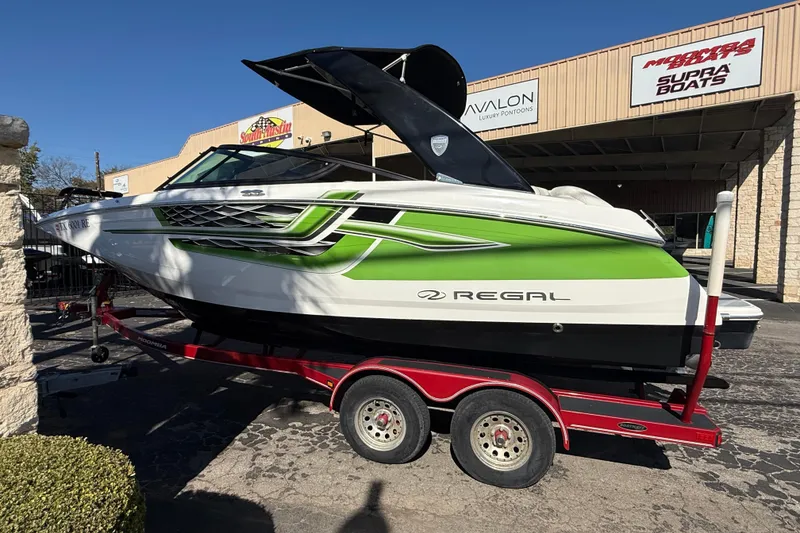 Slide: The Image of 2018 Regal 22 FasDeck boat with green accents on a red trailer. - 3