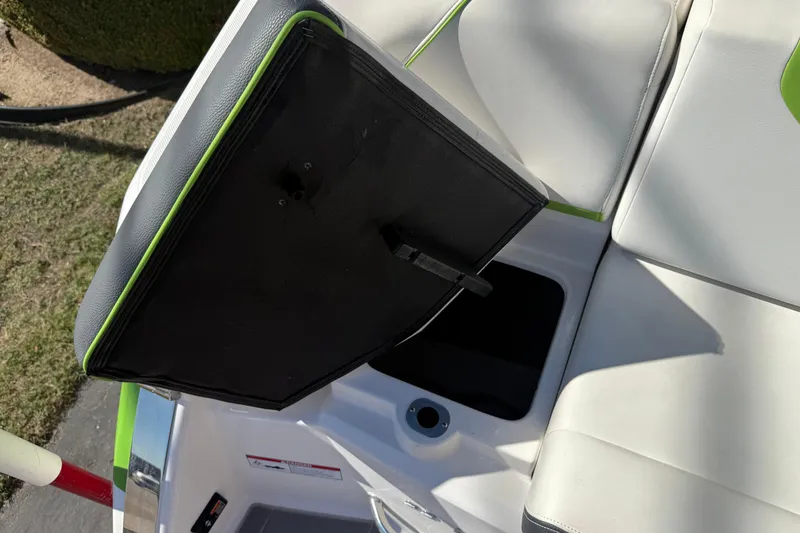 Slide: The Image of 2018 Regal 22 FasDeck boat seat with storage compartment open, featuring white and green upholstery. - 5