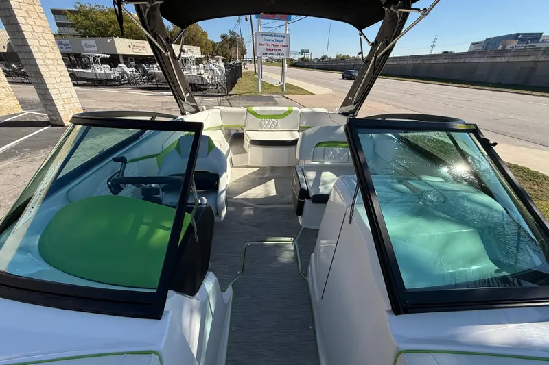 Slide: The Image of 2018 Regal 22 FasDeck boat interior with green and white seating, parked outdoors. - 7