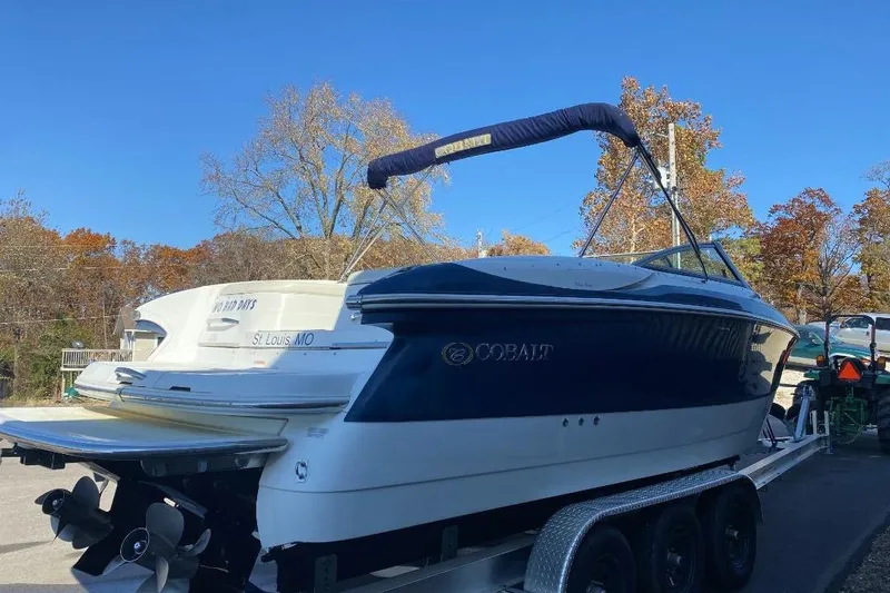 Slide: The Image of 2002 Cobalt 282 boat on trailer, blue and white, parked outdoors. - 4