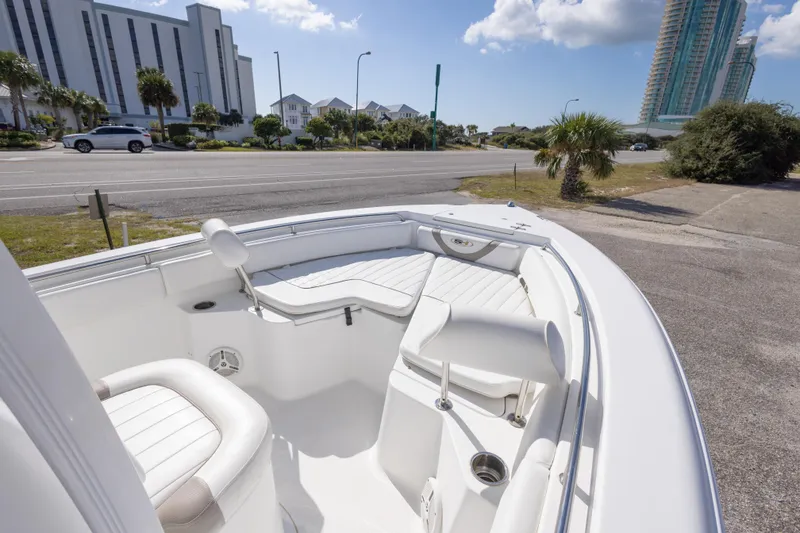Slide: The Image of 2012 Sea Hunt Ultra 225 boat interior with white seating, parked near a coastal road. - 19