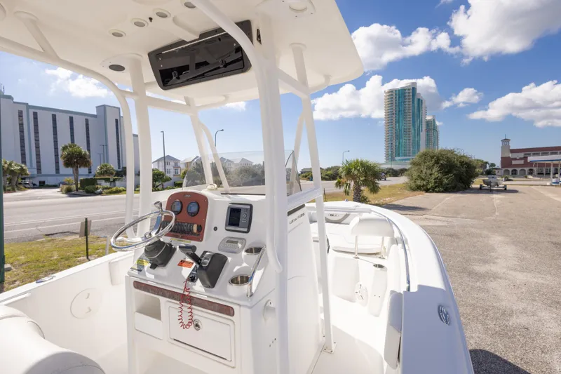 Slide: The Image of 2012 Sea Hunt Ultra 225 boat parked near modern buildings under a clear blue sky. - 23
