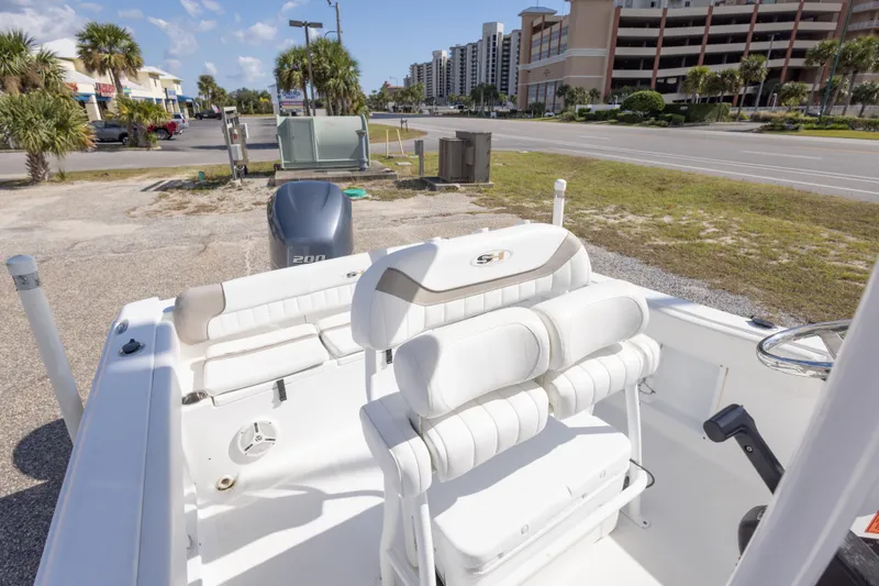 Slide: The Image of 2012 Sea Hunt Ultra 225 boat interior with seating and motor, parked near buildings. - 26