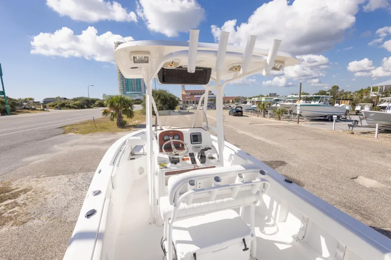 Slide: The Image of 2012 Sea Hunt Ultra 225 boat with console, parked near marina under blue sky. - 28