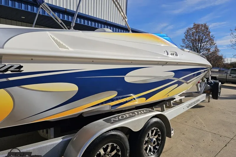 Slide: The Image of 2010 Sunsation 288 MID-CABIN boat with vibrant blue and yellow graphics on a trailer. - 12