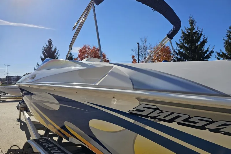 Slide: The Image of 2010 Sunsation 288 MID-CABIN boat with vibrant graphics, parked outdoors under clear sky. - 28