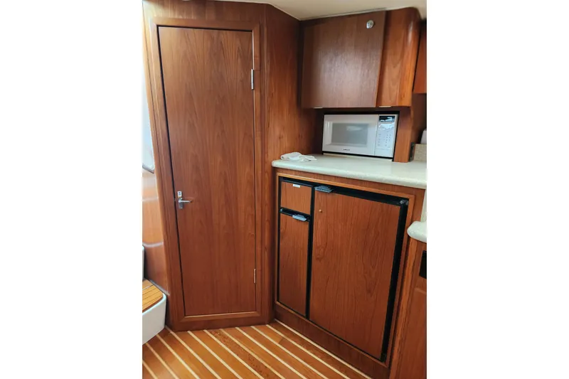 Slide: The Image of 2001 Tiara Yachts 3500 Open interior with wood cabinetry, microwave, and compact fridge. - 12