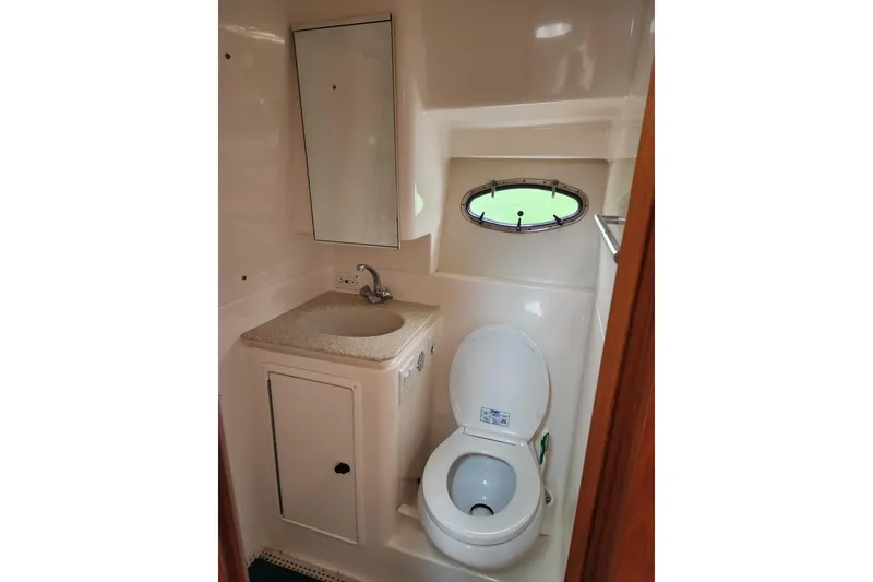 Slide: The Image of 2001 Tiara Yachts 3500 Open bathroom with sink, toilet, and porthole window. - 18