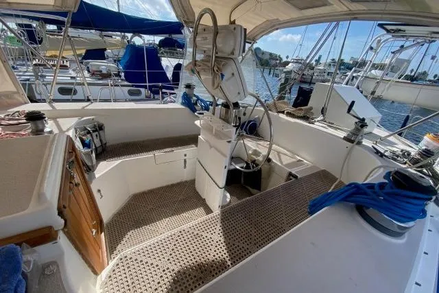 Slide: The Image of 1988 Morgan 44 sailboat cockpit with steering wheel, marina view, and nautical equipment. - 12