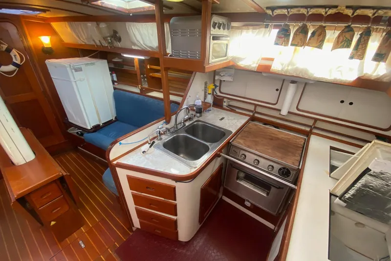 Slide: The Image of 1988 Morgan 44 yacht interior with kitchen, sink, stove, and seating area. - 17