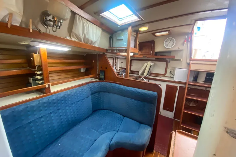 Slide: The Image of 1988 Morgan 44 yacht interior with blue seating, wooden accents, and nautical decor. - 19