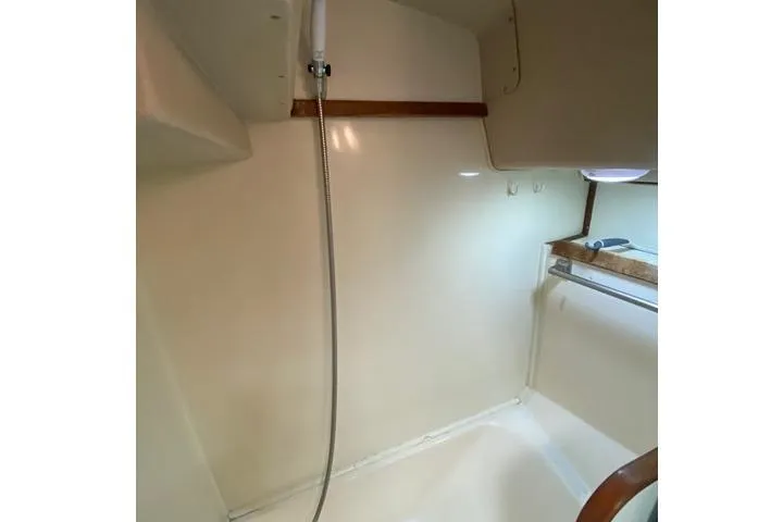 Slide: The Image of 1988 Morgan 44 yacht interior shower with white walls and wooden accents. - 32