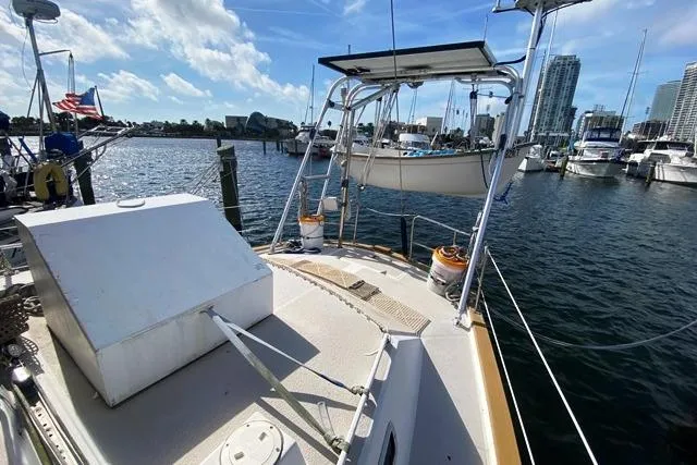 Slide: The Image of 1988 Morgan 44 sailboat docked in marina with city skyline and American flag. - 8