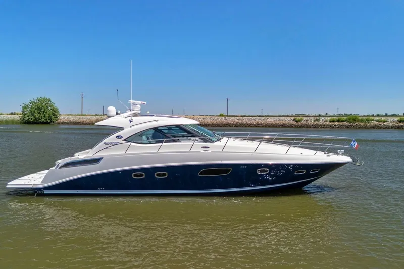 Slide: The Image of 2009 Sea Ray 470 Sundancer yacht cruising on a calm river under clear blue skies. - 12