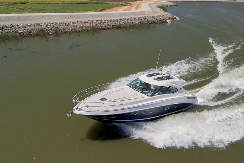 Slide: The Image of 2009 Sea Ray 470 Sundancer cruising on a calm river, creating a wake. - 8