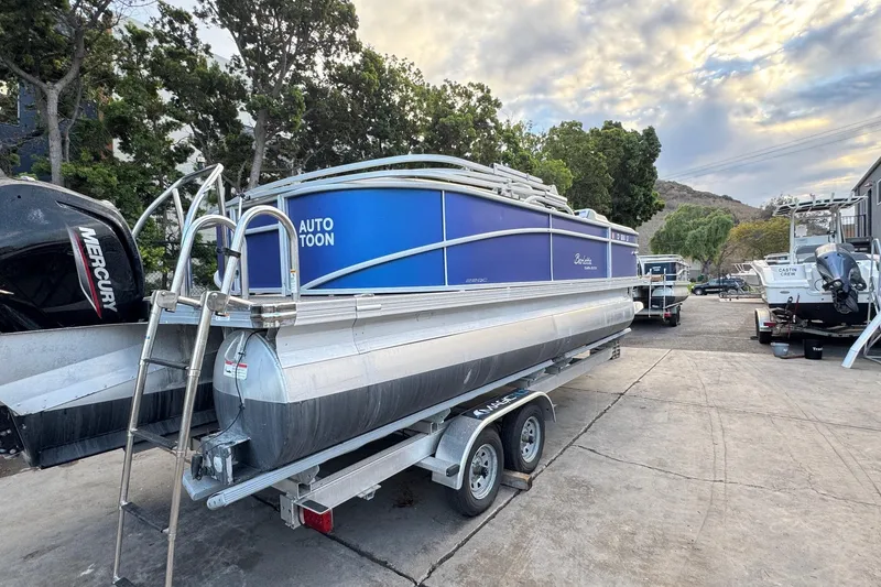 Slide: The Image of 2023 Barletta ARIA 22QC pontoon boat on trailer, parked outdoors under cloudy sky. - 15