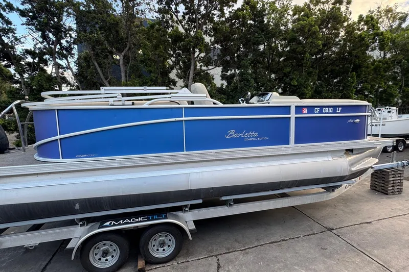 Slide: The Image of 2023 Barletta ARIA 22QC pontoon boat on trailer, blue exterior, parked outdoors. - 18