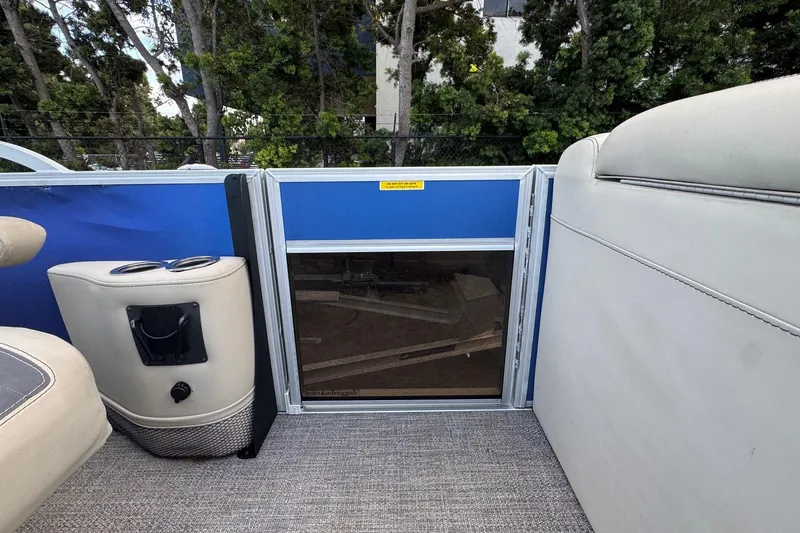 Slide: The Image of 2023 Barletta ARIA 22QC boat interior with cup holder and seating, surrounded by trees. - 38