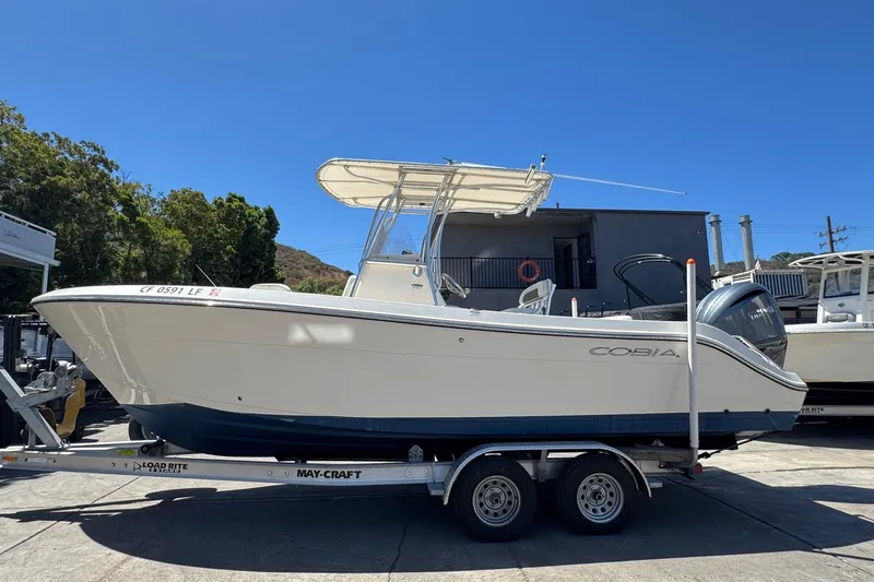 The Image of 2022 Cobia 237 Center Console boat docked under clear blue sky with palm trees. - 0