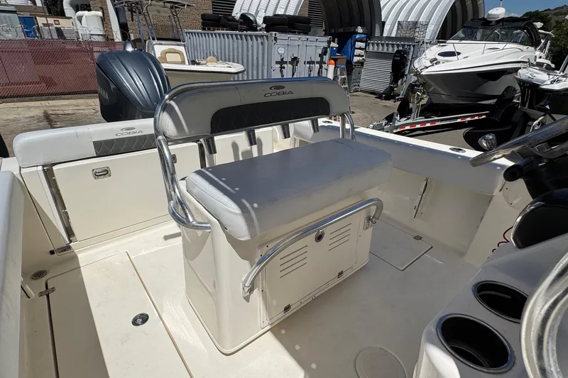 Slide: The Image of 2022 Cobia 237 Center Console boat docked in a marina, surrounded by other vessels. - 12