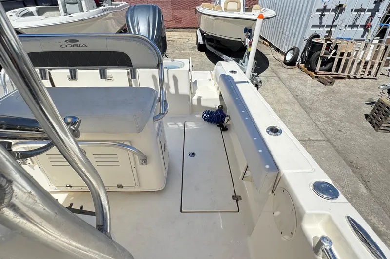 Slide: The Image of 2022 Cobia 237 Center Console boat with motor, docked alongside two other boats. - 13
