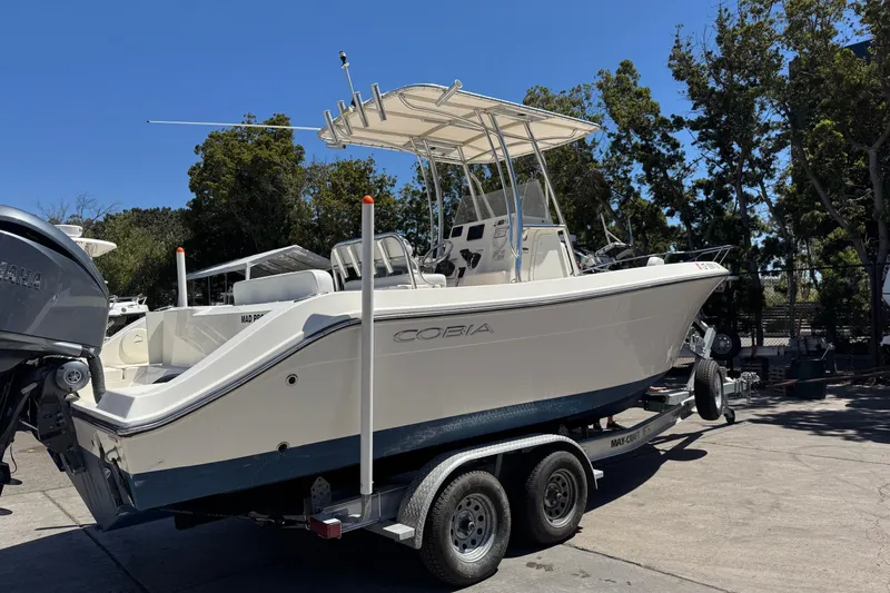 Slide: The Image of 2022 Cobia 237 Center Console boat docked near palm trees and hotel. - 2
