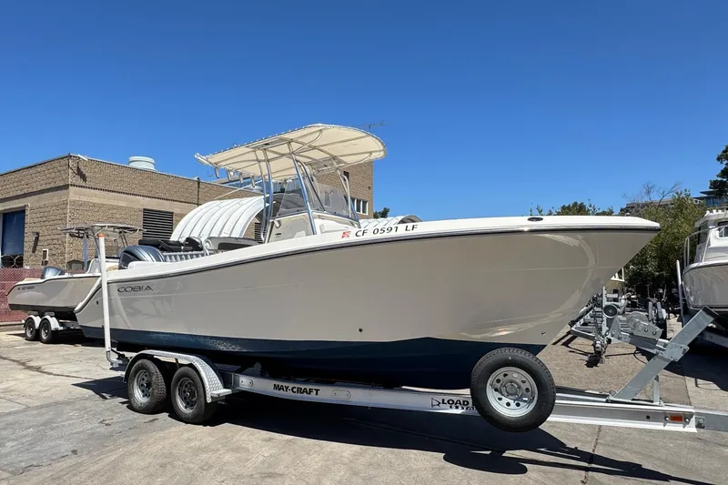 Slide: The Image of 2022 Cobia 237 Center Console boat docked near palm trees and hotel. - 3