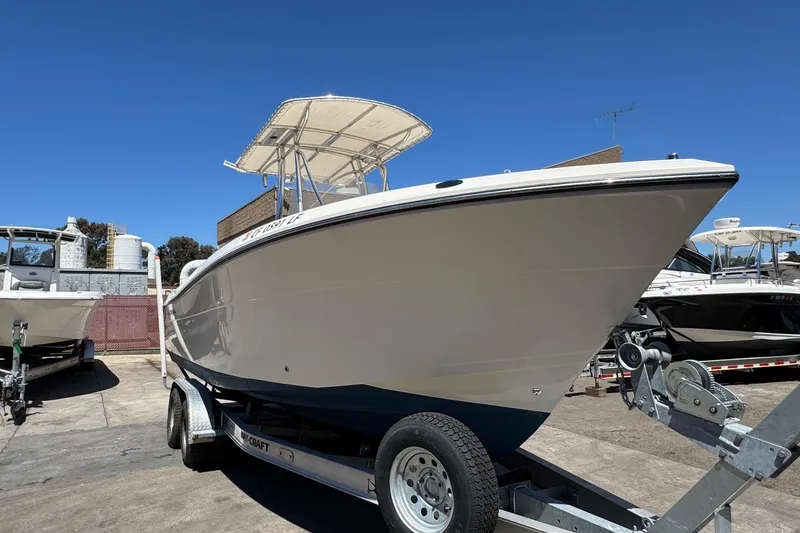 Slide: The Image of 2022 Cobia 237 Center Console boat docked by palm trees under clear blue sky. - 4