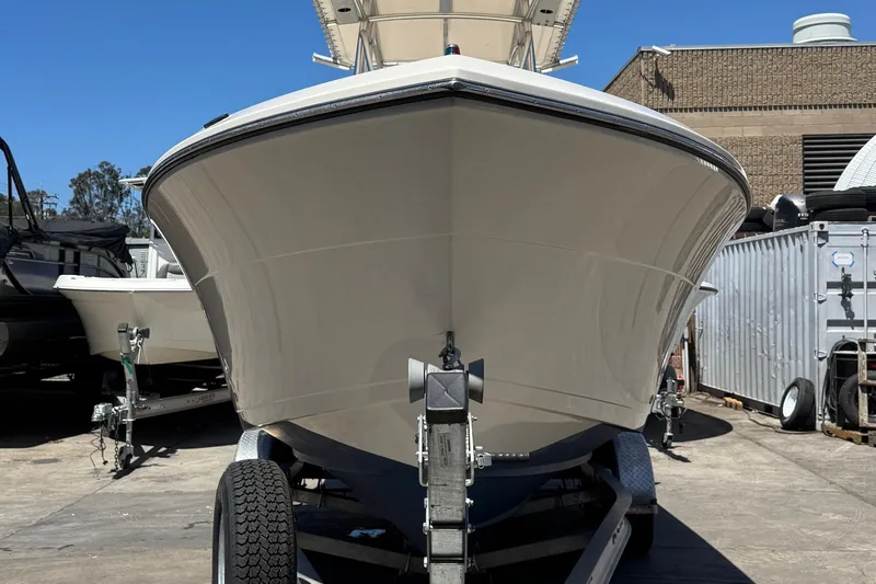Slide: The Image of 2022 Cobia 237 Center Console boat docked under clear blue sky with palm trees. - 5