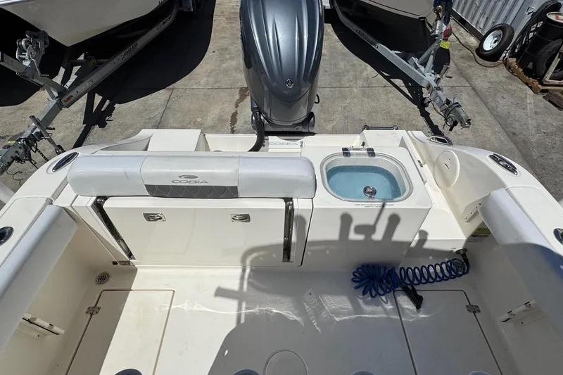 Slide: The Image of 2022 Cobia 237 Center Console boat docked under clear blue sky with palm trees. - 9