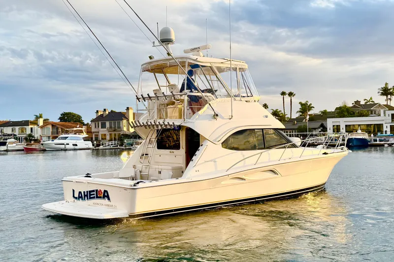 Slide: The Image of 2001 Riviera 40 Flybridge yacht cruising in a scenic harbor setting. - 2