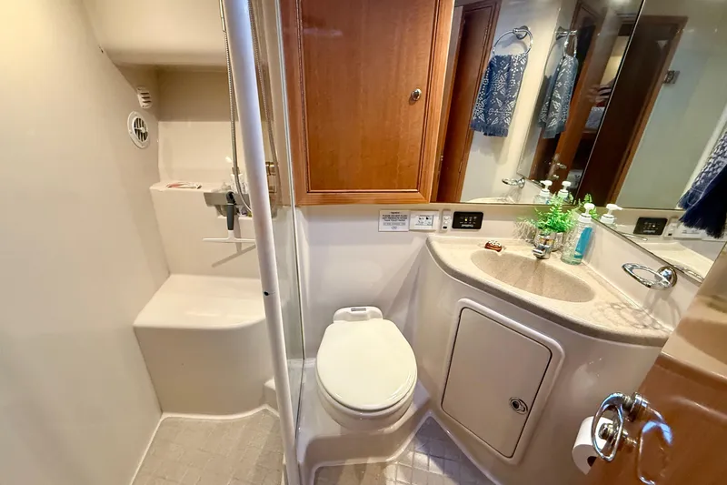 Slide: The Image of 2001 Riviera 40 Flybridge bathroom with shower, sink, and toilet, featuring wood cabinetry. - 32